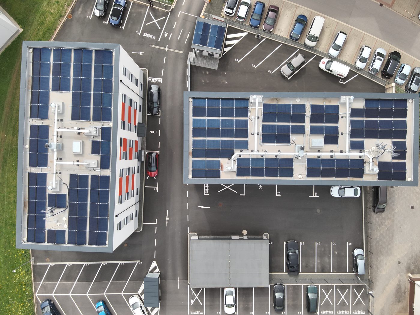 Fotovoltaika na plochých střechách dvou vícepodlažních budov, pohled z dronu