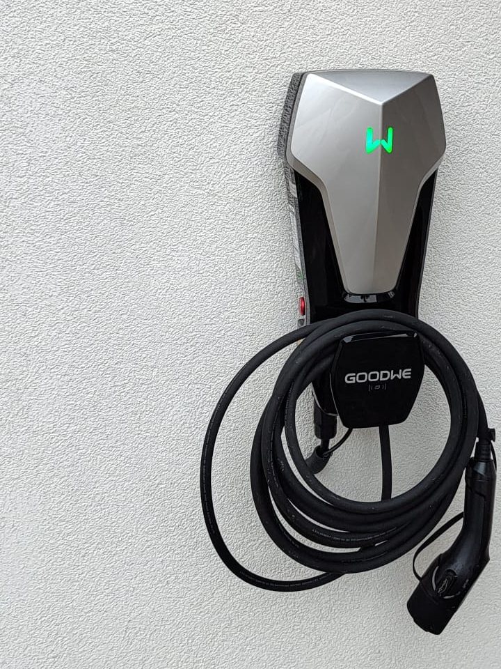 Wallbox na bílé fasádě u vchodu